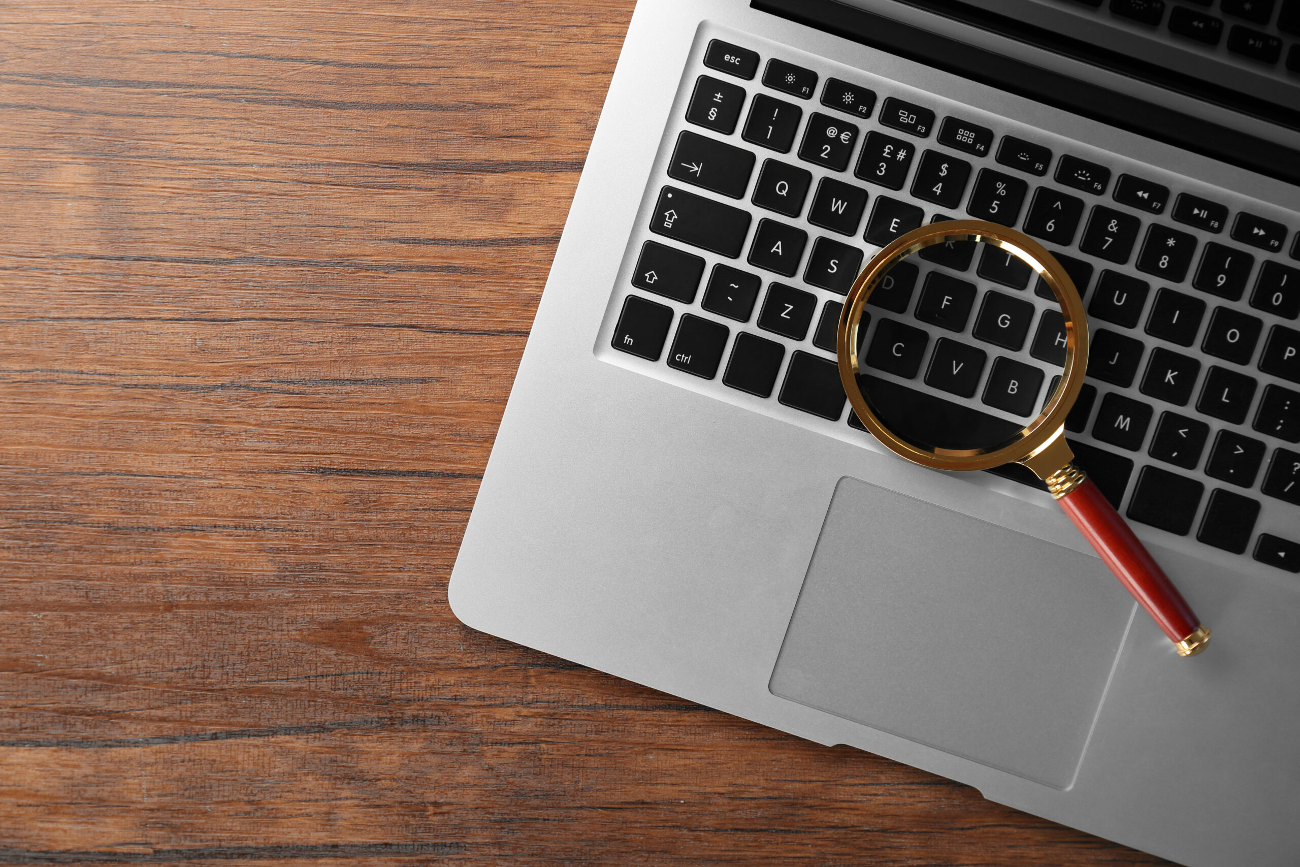 Eine Lupe liegt auf der Tastatur eines Laptops